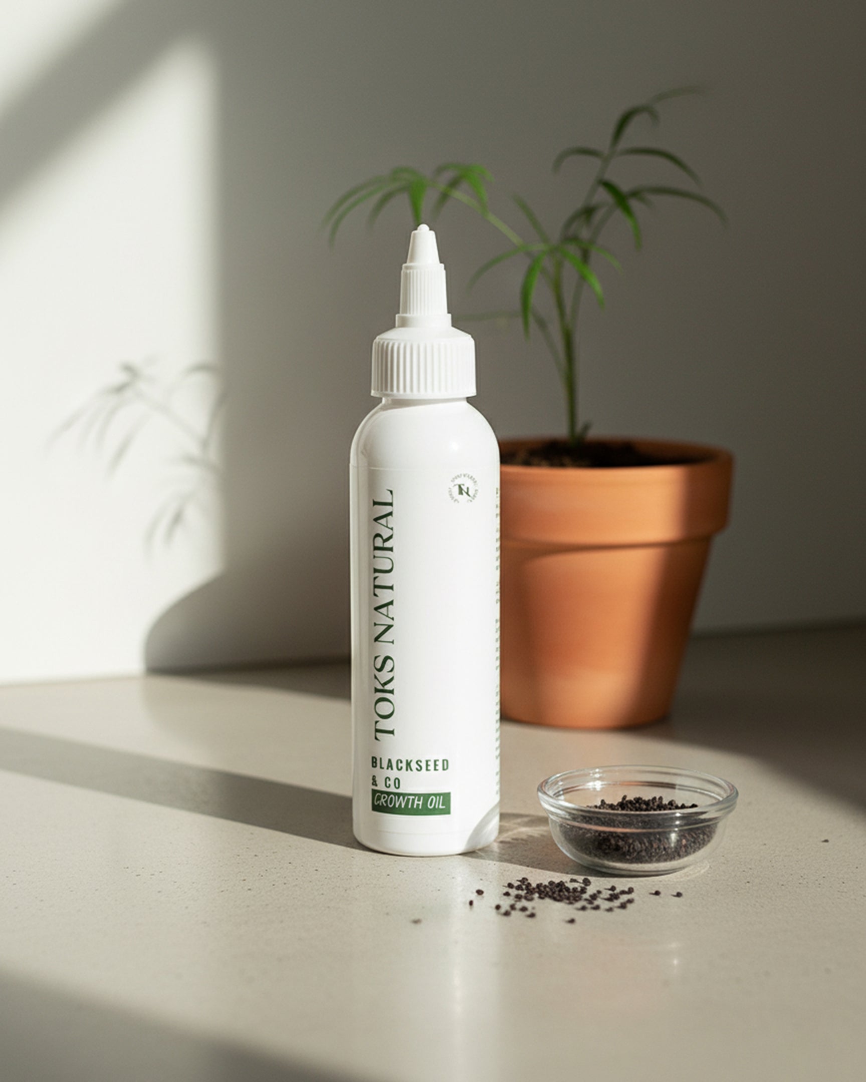 White bottle labeled 'TOKS NATURAL' on a surface with a plant and small bowl in the background.