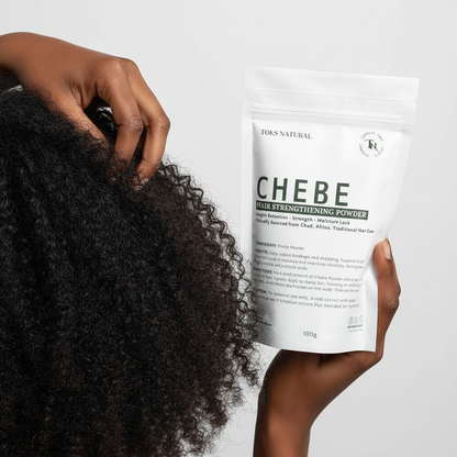 Person holding a package of TOKS NATURAL CHEBE hair strengthening powder with curly hair.