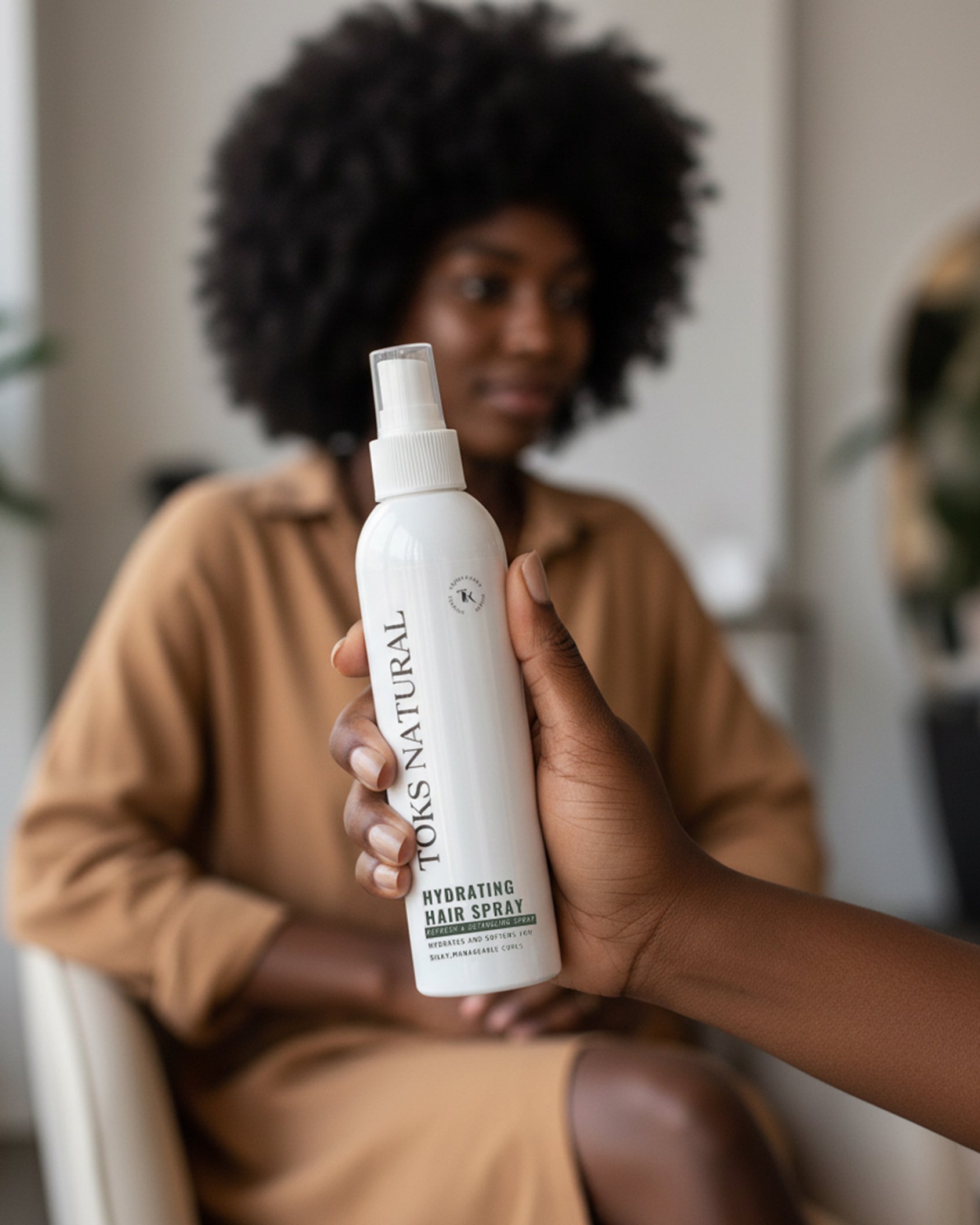 Person holding a bottle of 'Toks Natural' hair spray with a blurred background