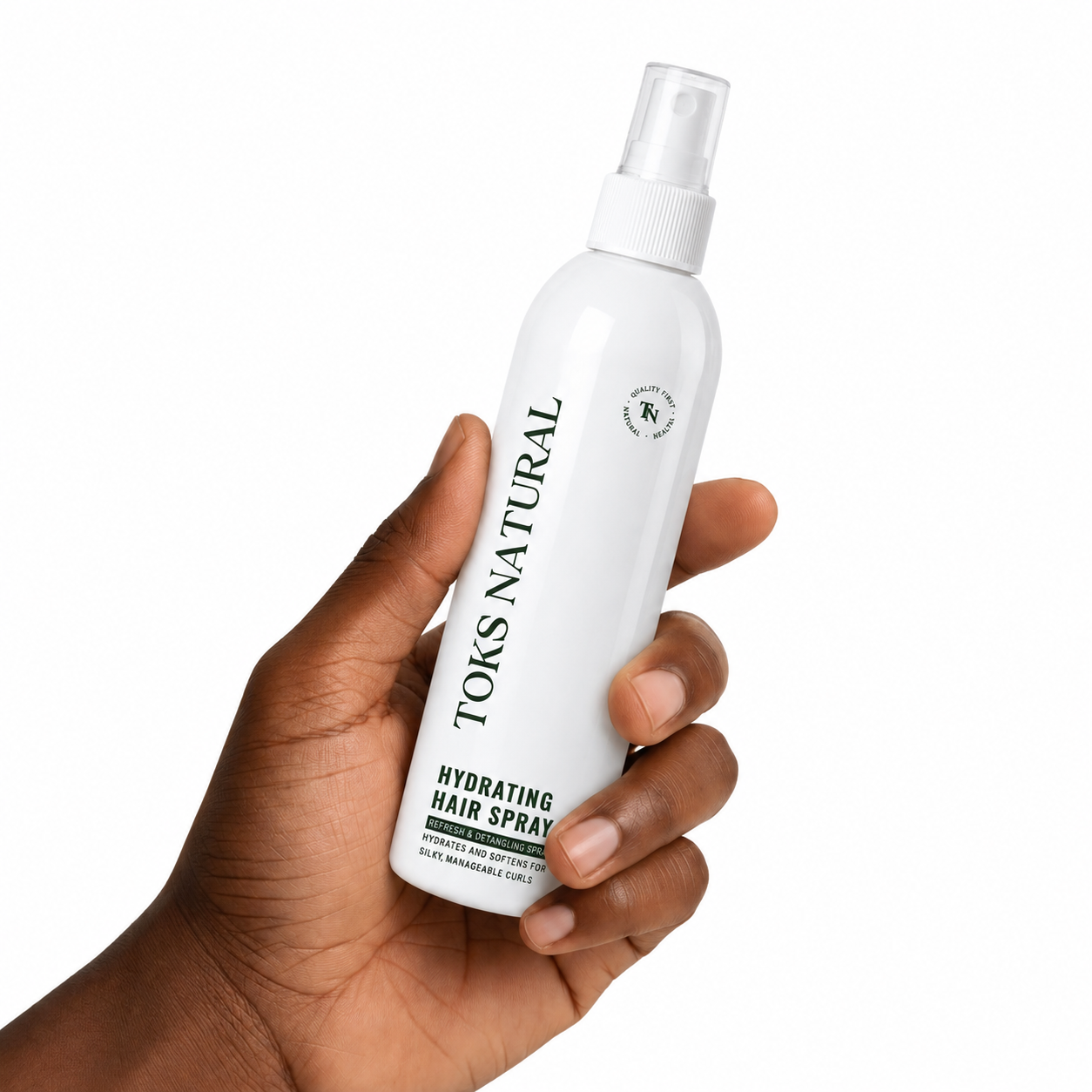 Hand holding a white bottle of TOKS NATURAL hydrating hair spray against a white background