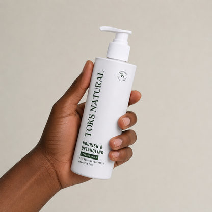 Hand holding a bottle of TOKS NATURAL hair product against a neutral background
