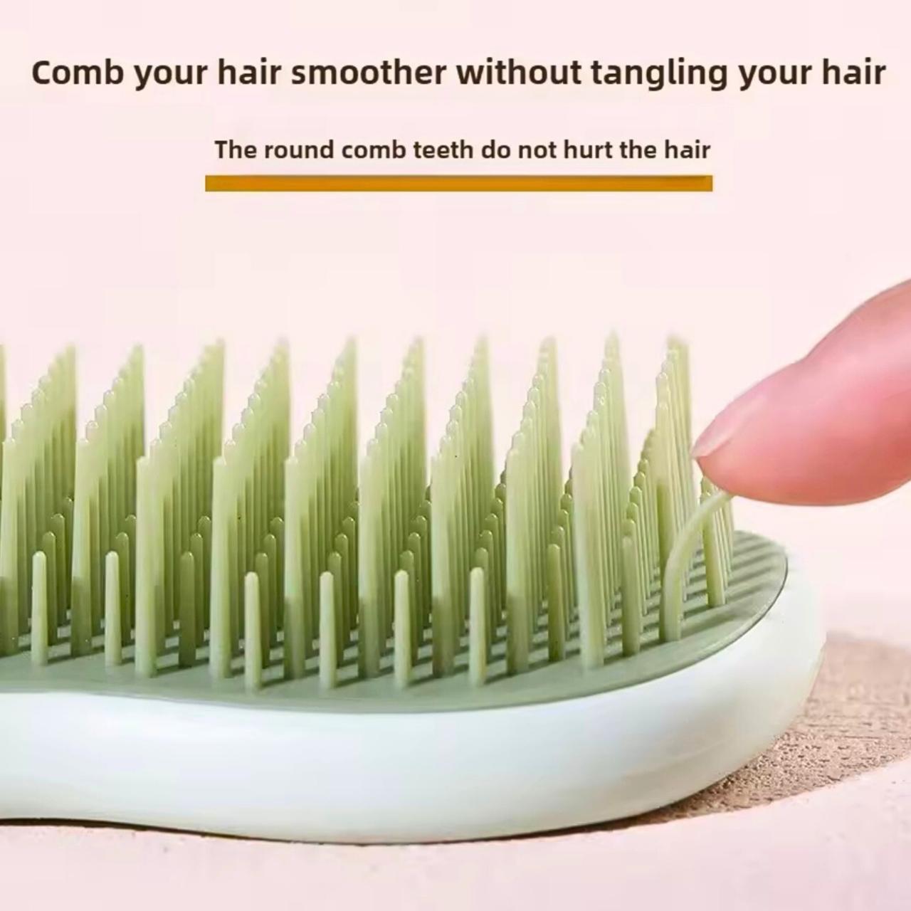 Hair comb with round teeth being held by a hand on a light pink background