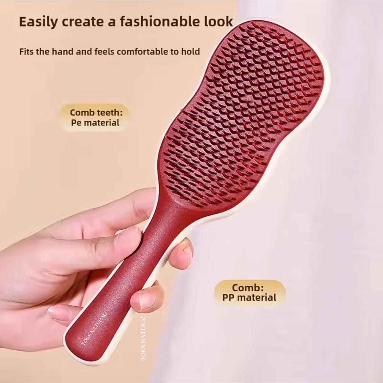 Red paddle brush held by a hand with text about material and use.