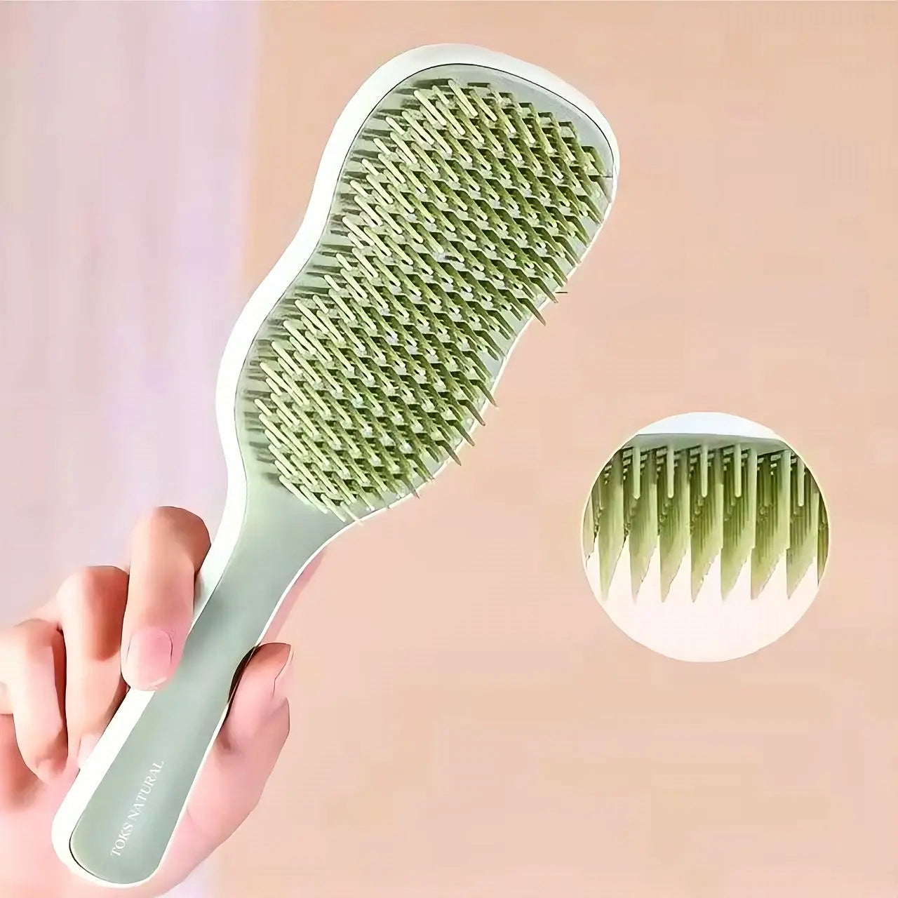 Green hairbrush held by a hand with an inset showing the bristle detail on a pink background