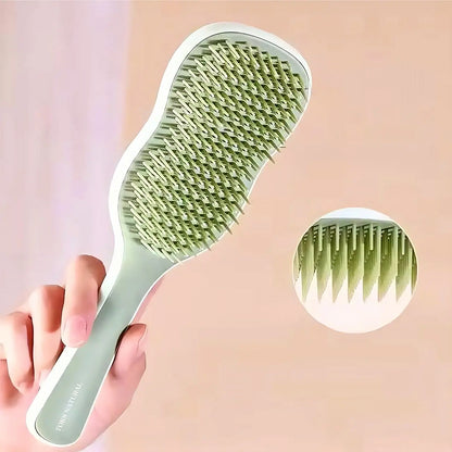 Green hairbrush held by a hand with an inset showing the bristle detail on a pink background