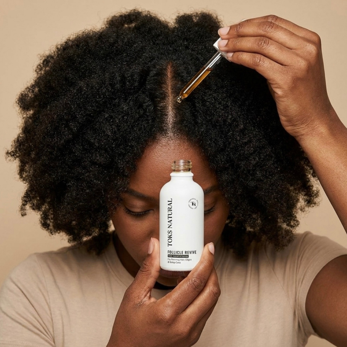 Person applying Tokes Natural hair product to their hair with a dropper.