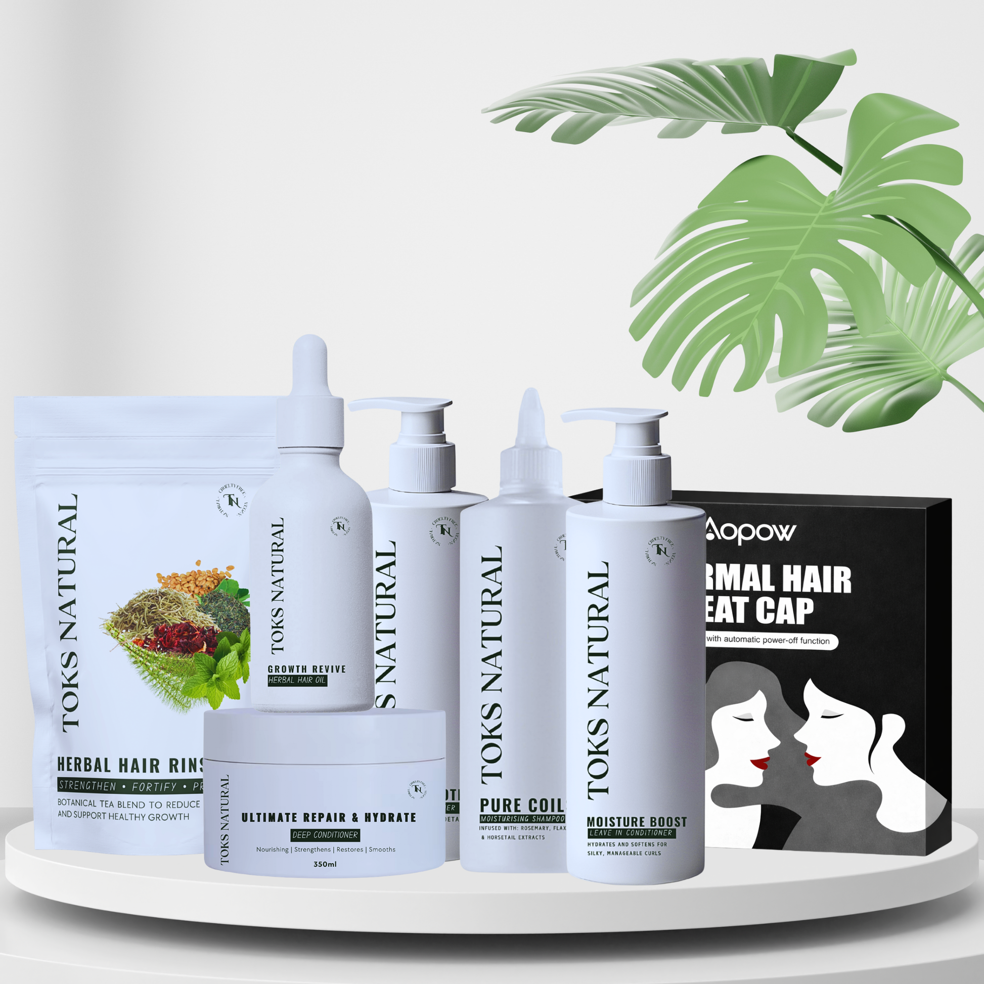Set of TOKS NATURAL hair care products on a white surface with green leaves in the background.