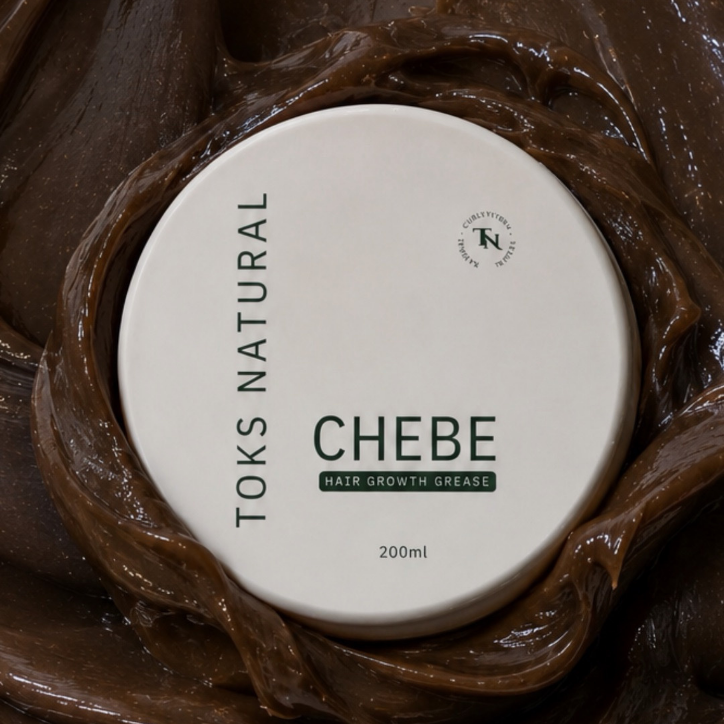 A round white lid labeled 'TOKS NATURAL CHEBE HAIR GROWTH GREASE 200ml' placed over a swirl of glossy dark brown grease, filling the frame.