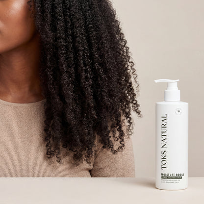 Woman with curly hair next to a bottle of TOKS NATURAL product on a beige background