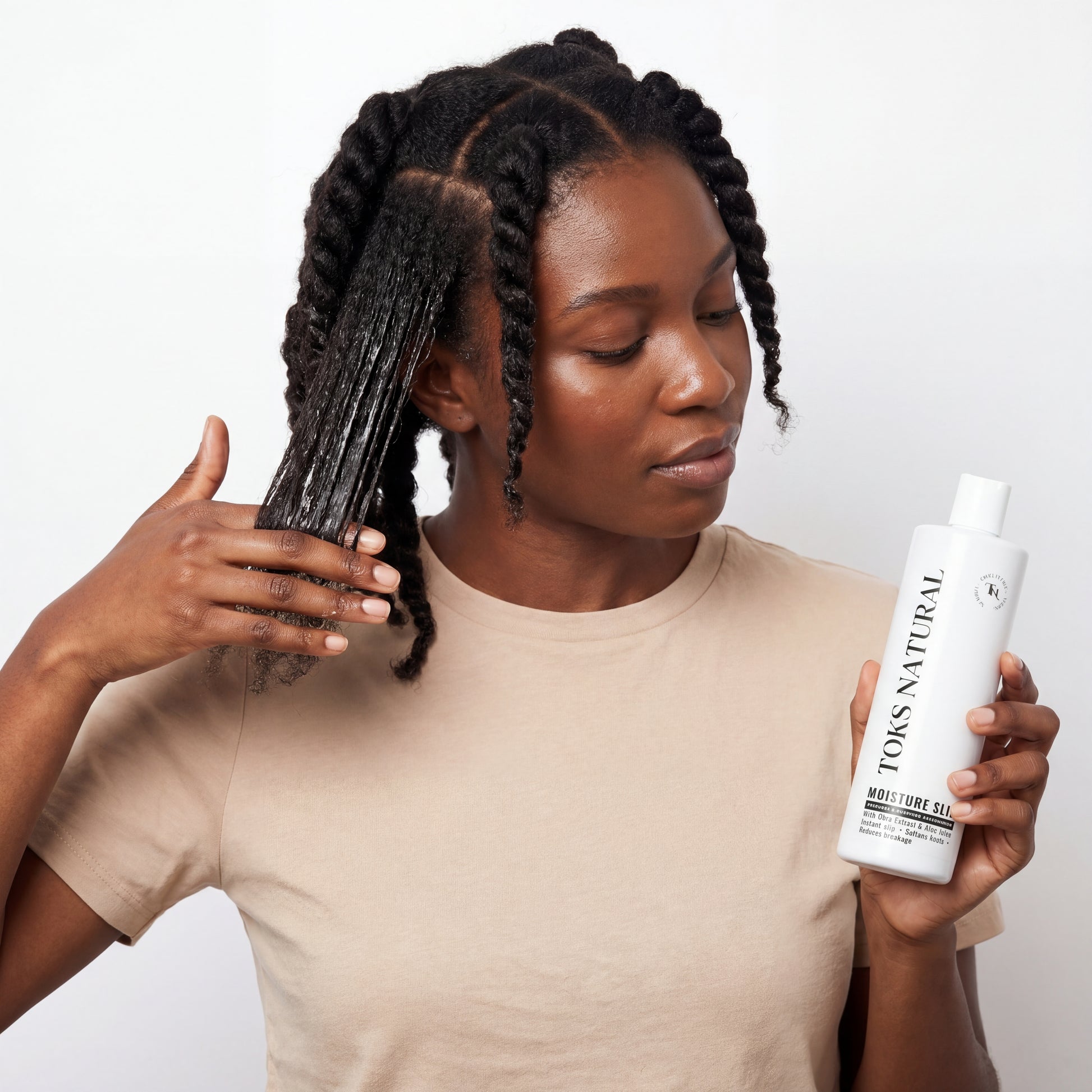 Woman with braided hair holding a bottle of Toks Natural product against a white background