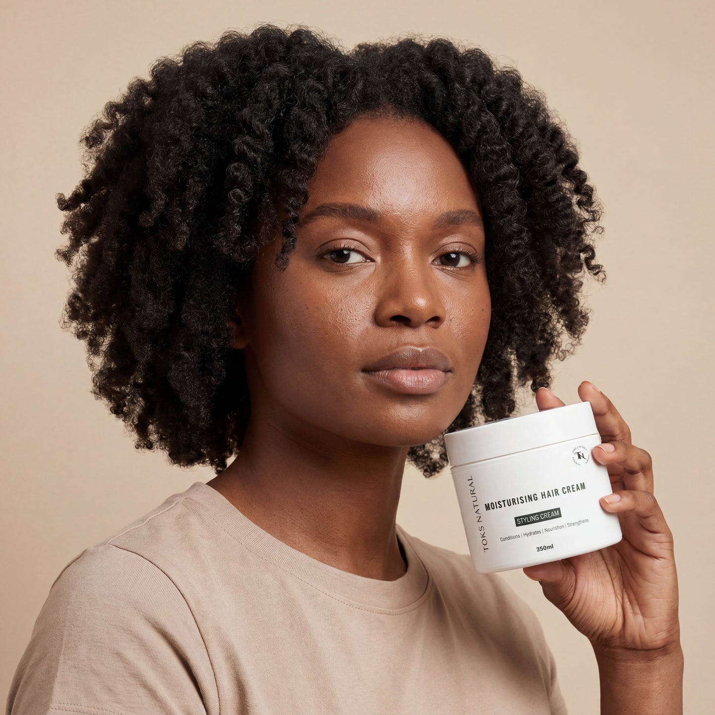 Woman holding a jar of hair care product against a beige background