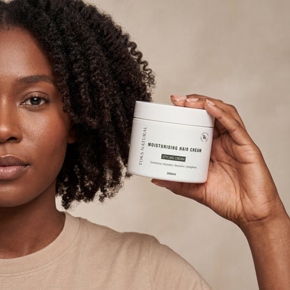 Woman holding a jar of Tork's Natural Moisturising Hair Cream against a neutral background