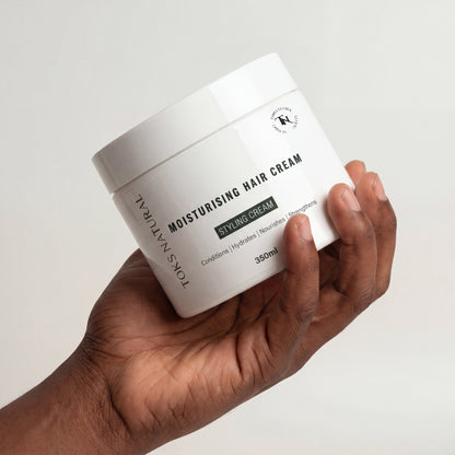 Hand holding a jar of Toks Natural Moisturising Hair Cream against a white background