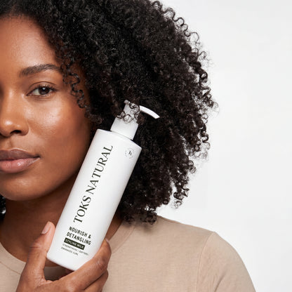 Woman holding a bottle of TOKS NATURAL hair product against a white background