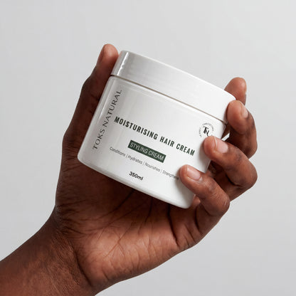 Hand holding a jar of TOKS Natural Moisturising Hair Cream against a plain background