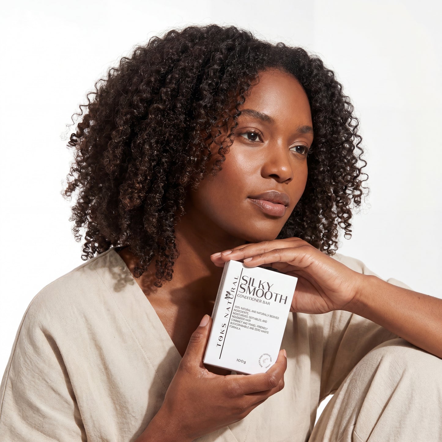 Woman holding a skincare product box with a plain background