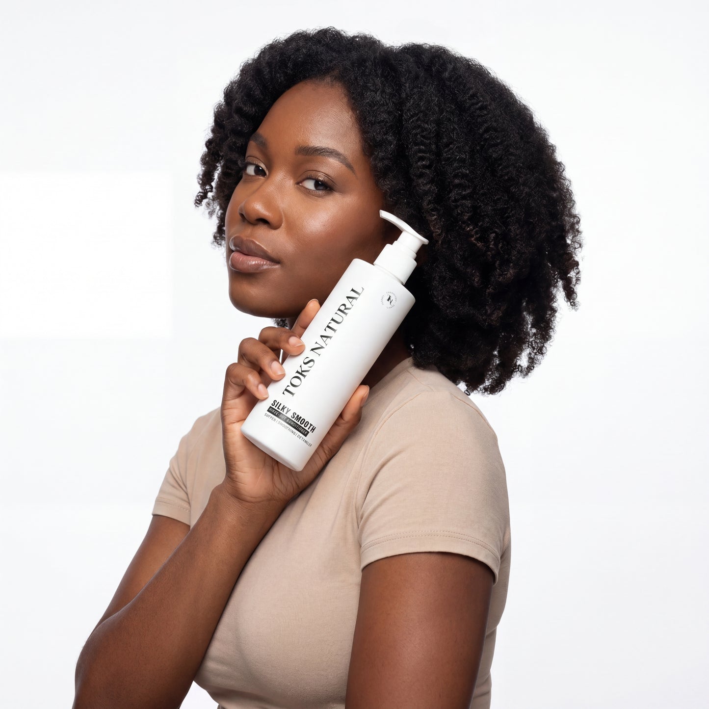 Woman holding a bottle of Tons of Natural hair product against a white background