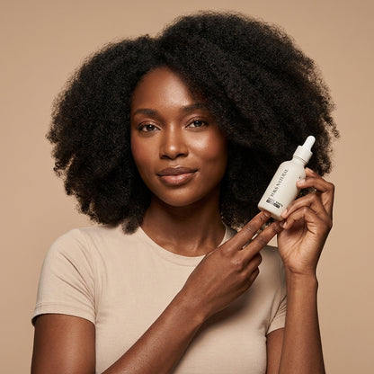 Woman holding a bottle of hair care product against a beige background