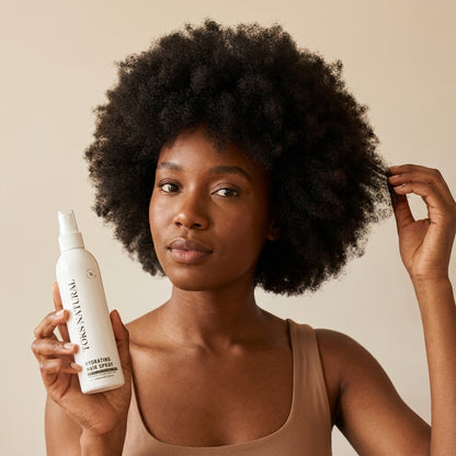 Woman holding a bottle of L'Oreal Paris hair product against a beige background