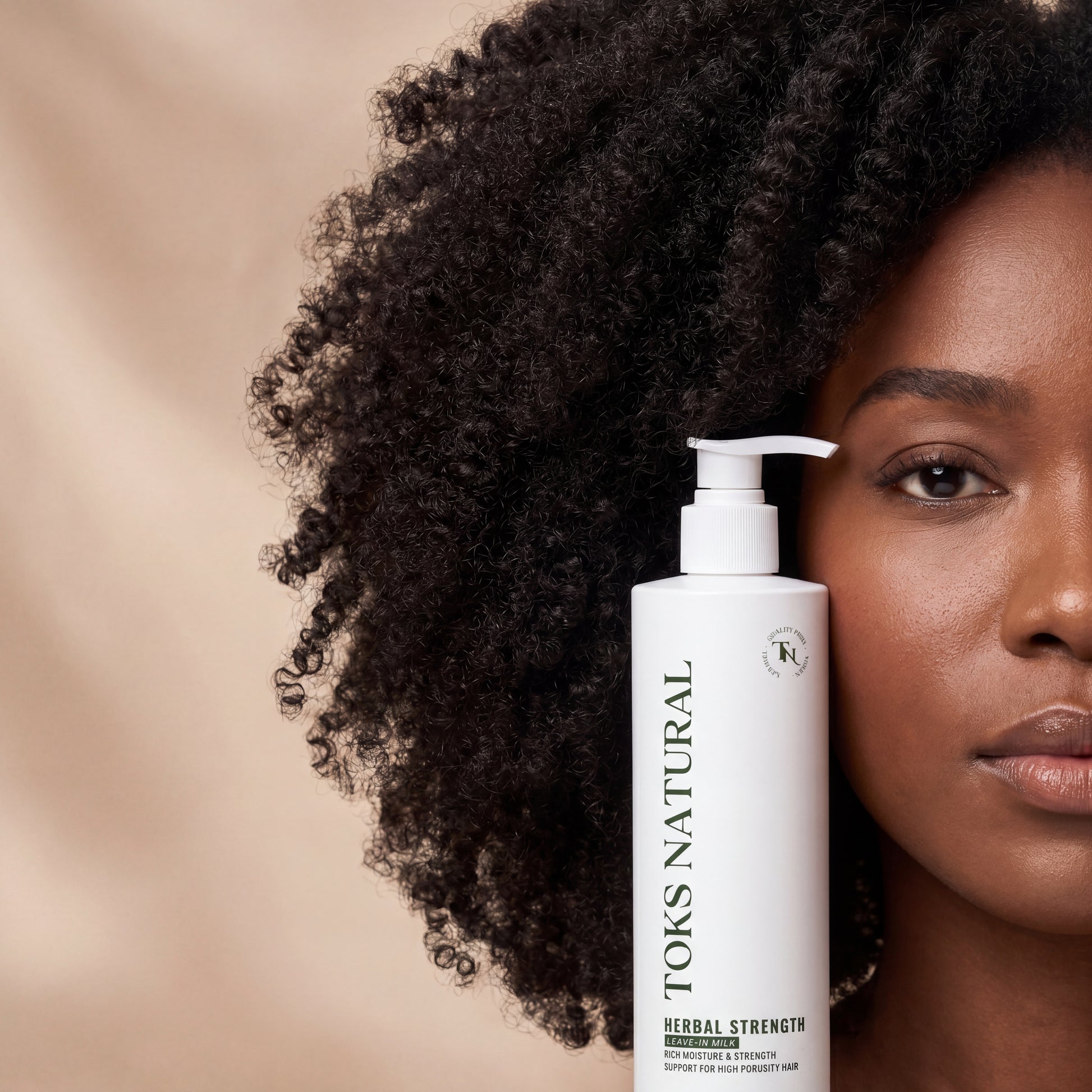 Woman with curly hair holding a bottle of TOKS NATURAL hair product against a beige background