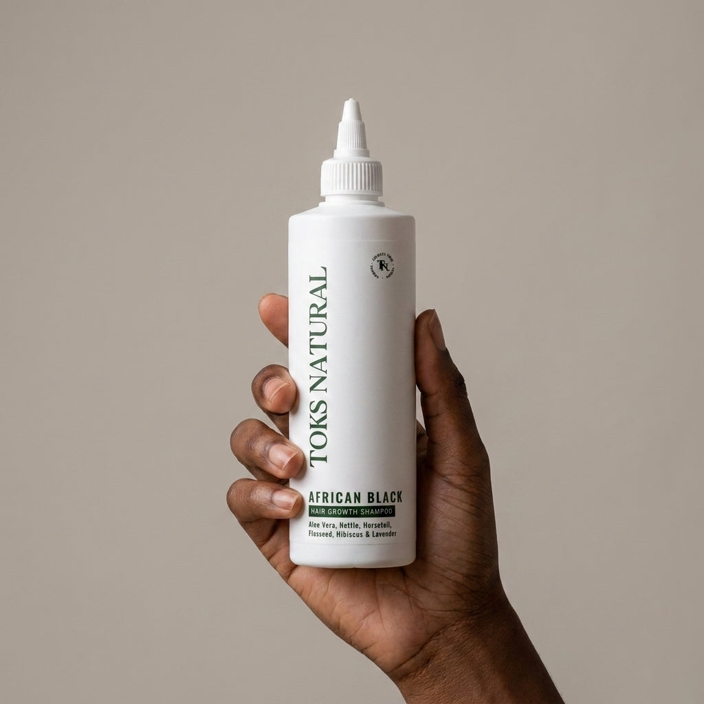 A hand holding a white squeeze bottle of Toks Natural African Black hair color against a solid beige background.