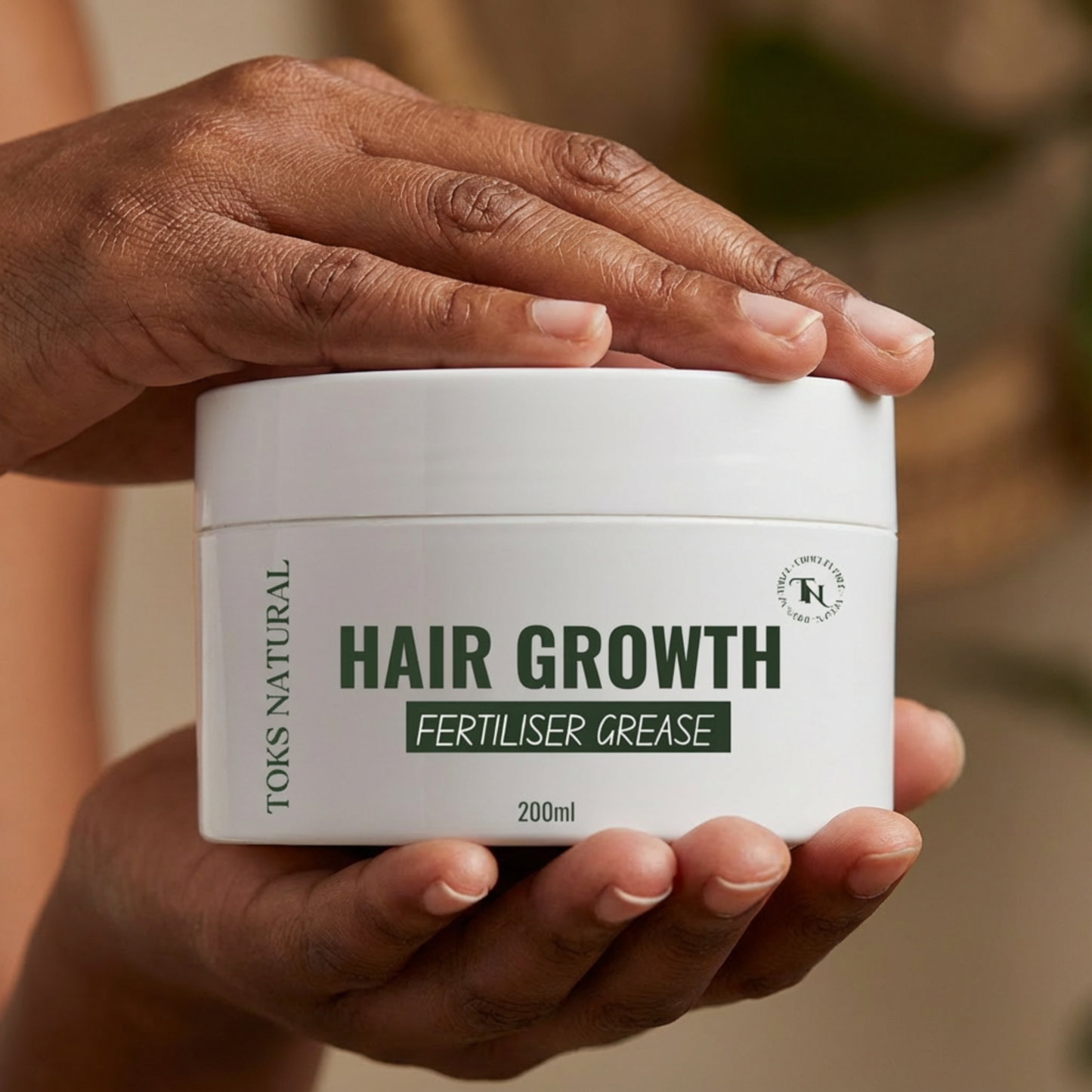 Hand holding a jar of 'Hair Growth Fertiliser Grease' by Torks Natural against a blurred background.