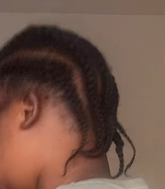 Close-up of a person with braided hair against a neutral background